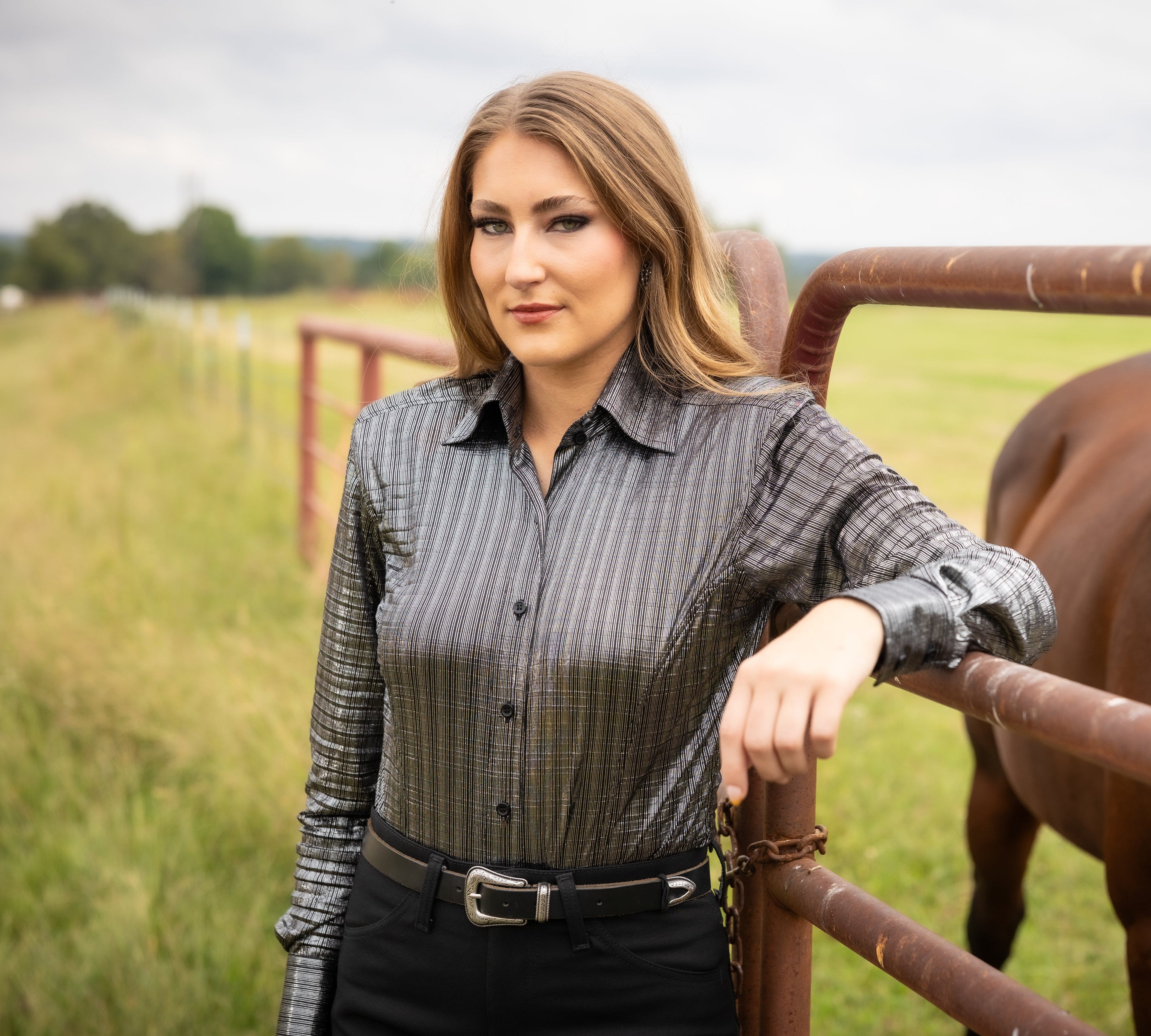 Model posing with horse in ranch setting wearing Onyx shirt from Kultured Rider's jewel collection.