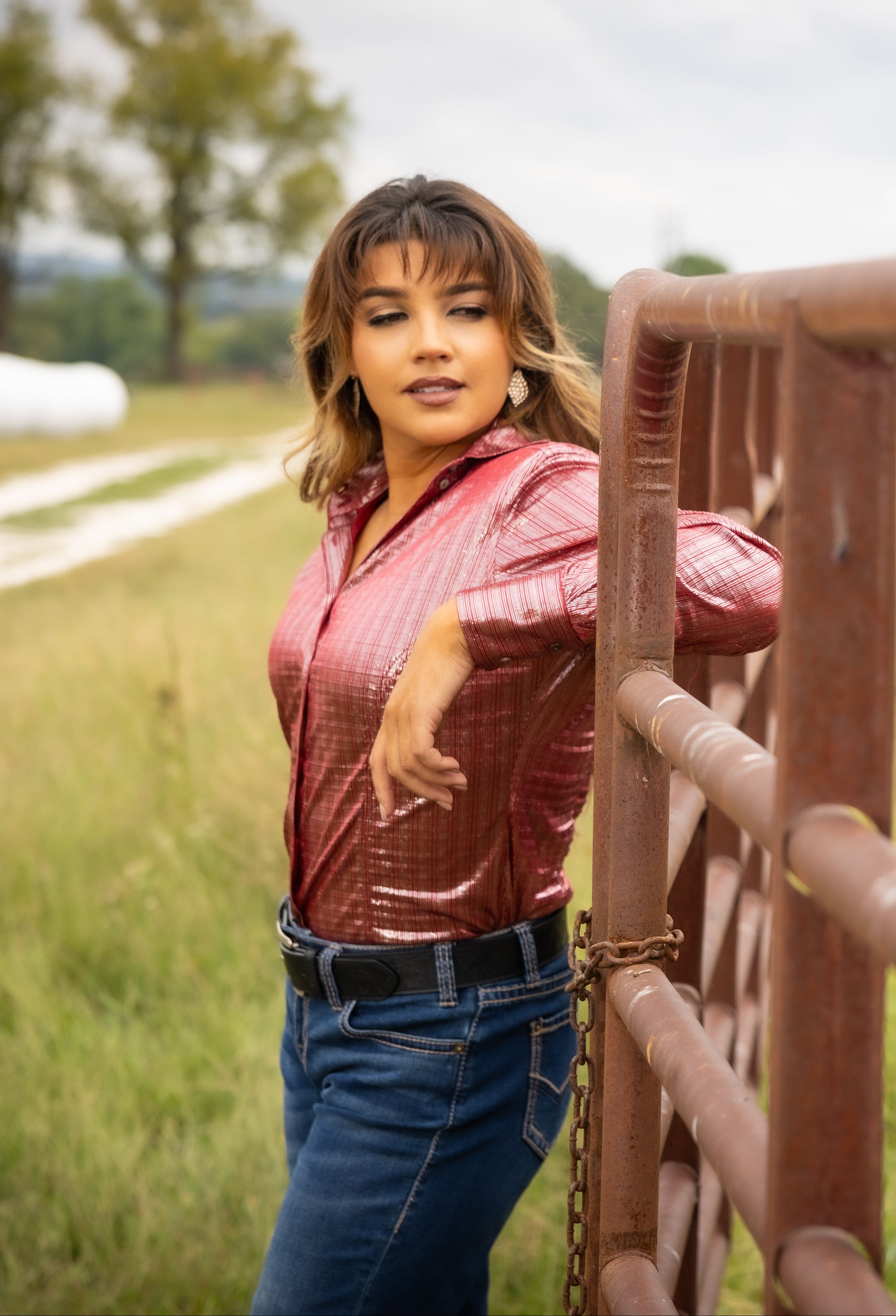 Model wearing Ruby shirt from Kultured Rider's jewel collection, posing in ranch setting with horse