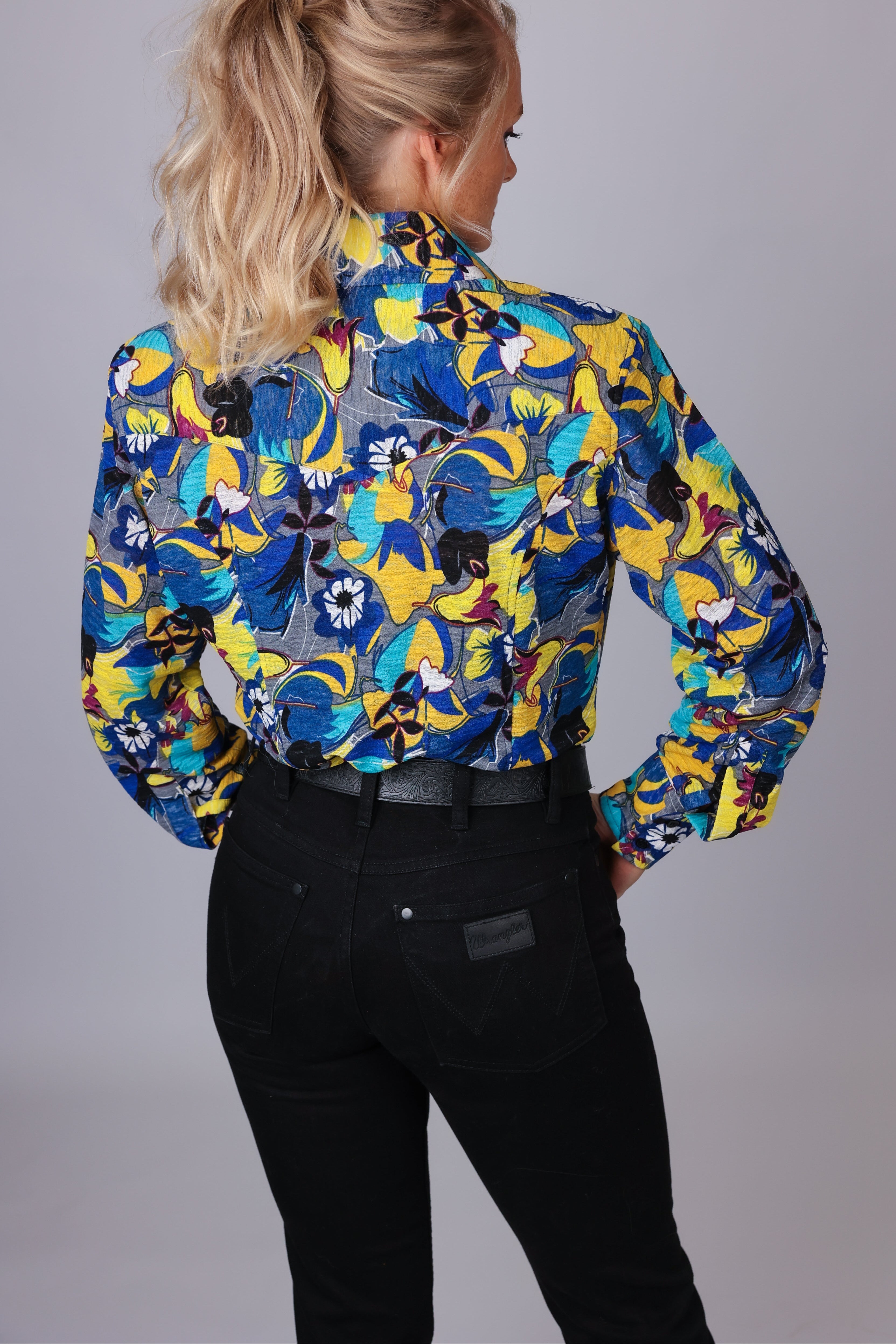 Woman posing in studio in jungle blue shirt from the Romina collection by Kultured Rider.
