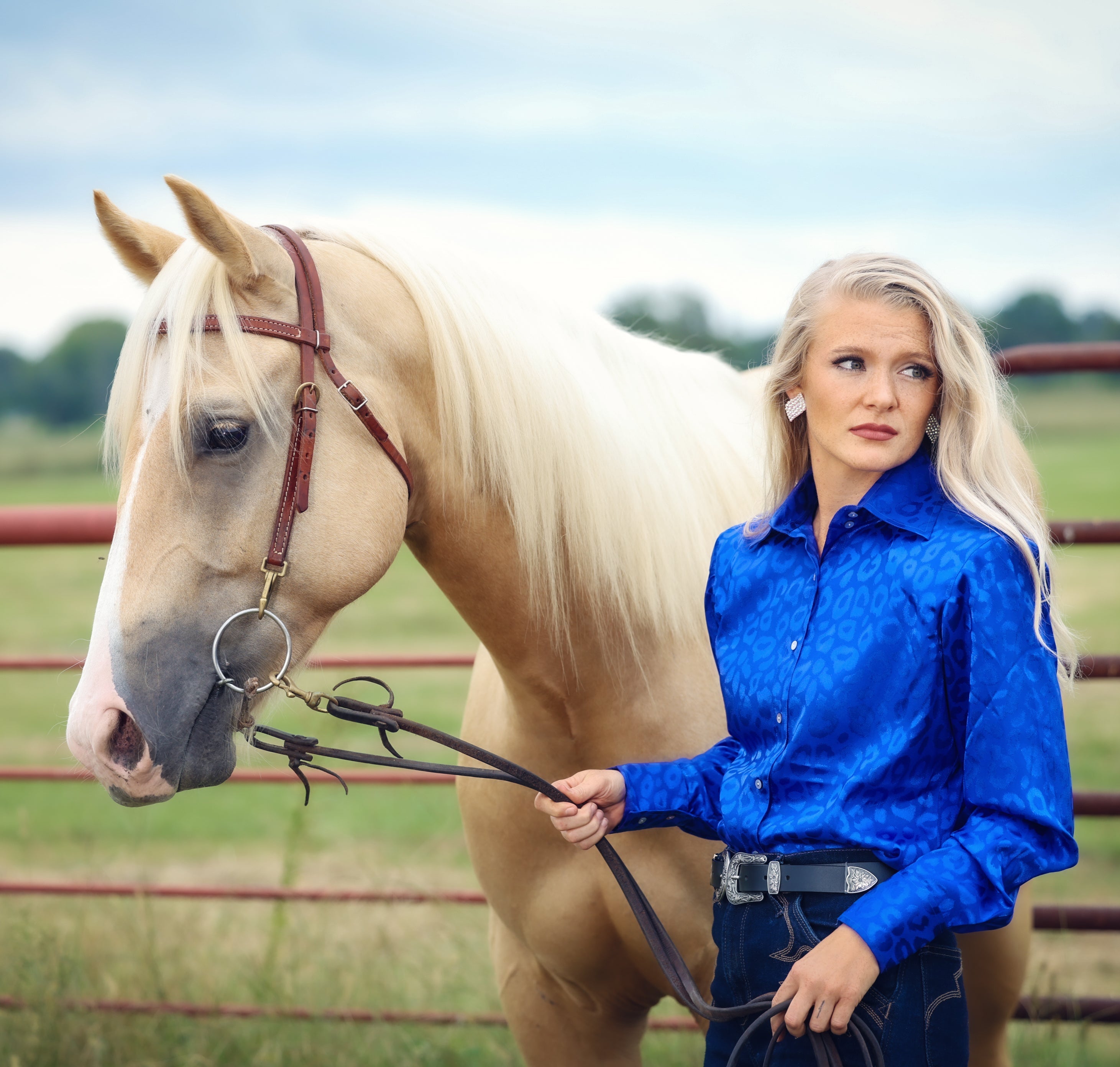 Model with horse posing in leopard blue shirt from the Faith collection by Kultured Rider in a green field.