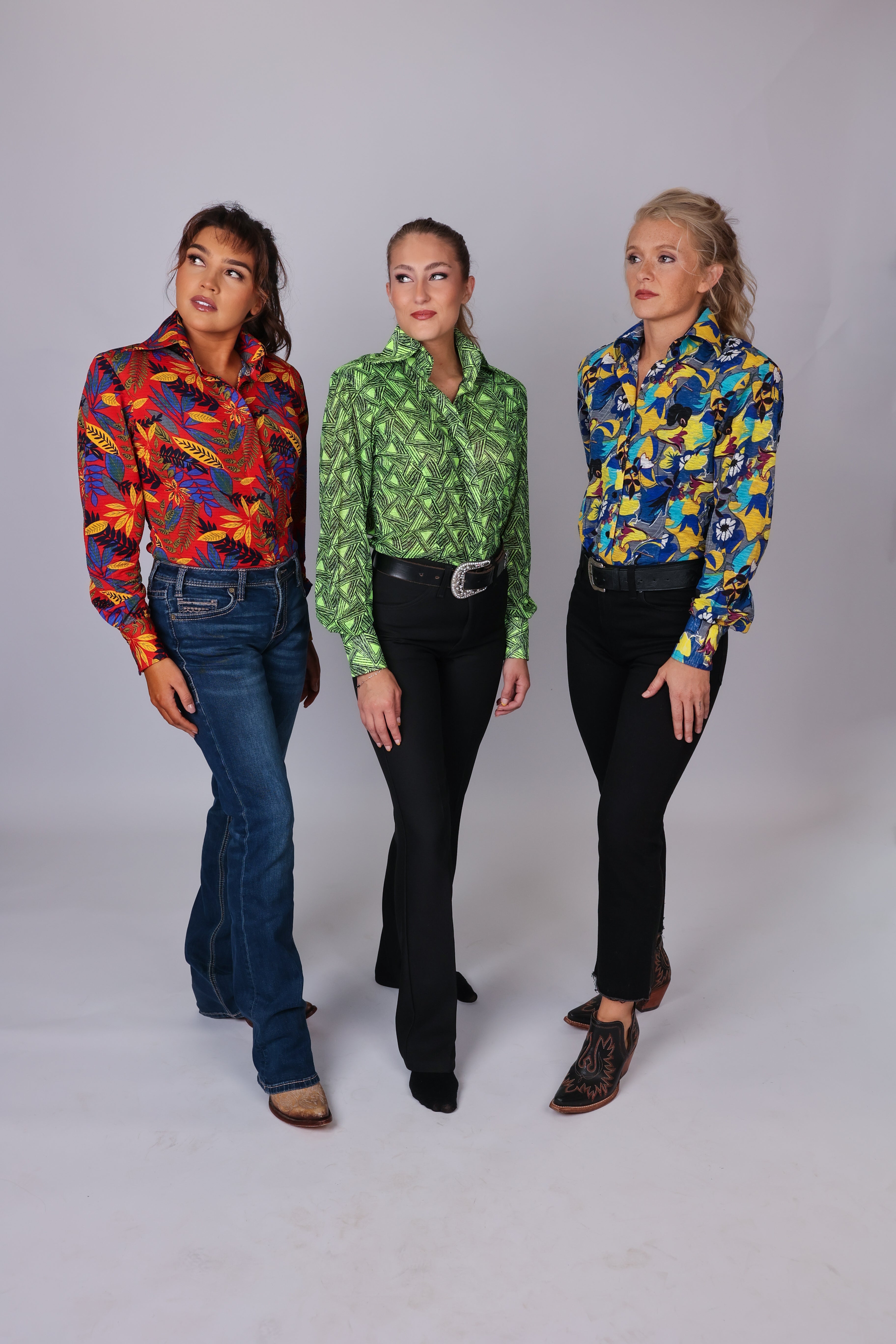 Three women pose in bright colorful shirts from the Romina collection by Kultured Rider.