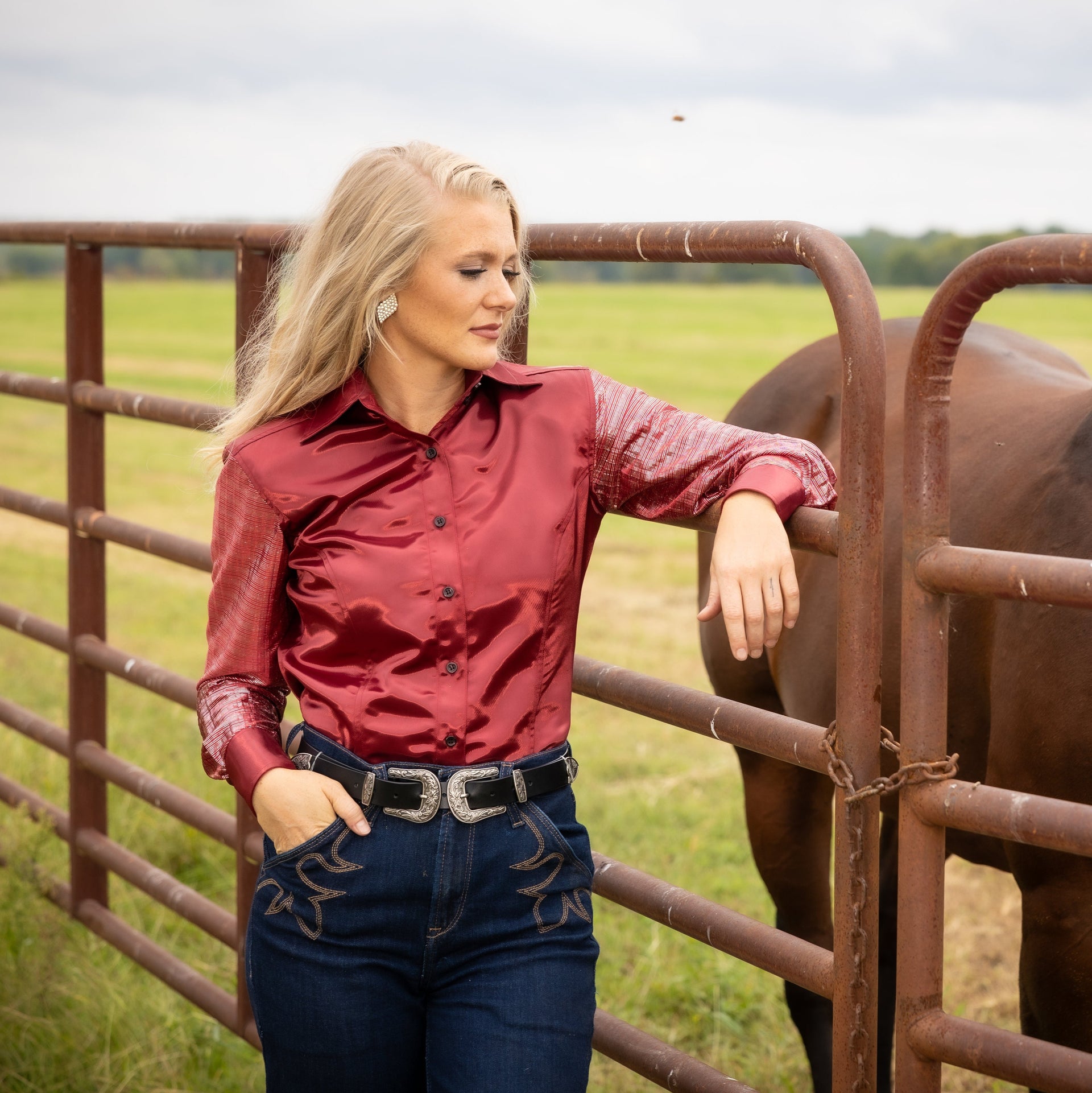 Model wearing Garnet shirt from Kultured Rider's jewel collection, posing in ranch setting with horse 