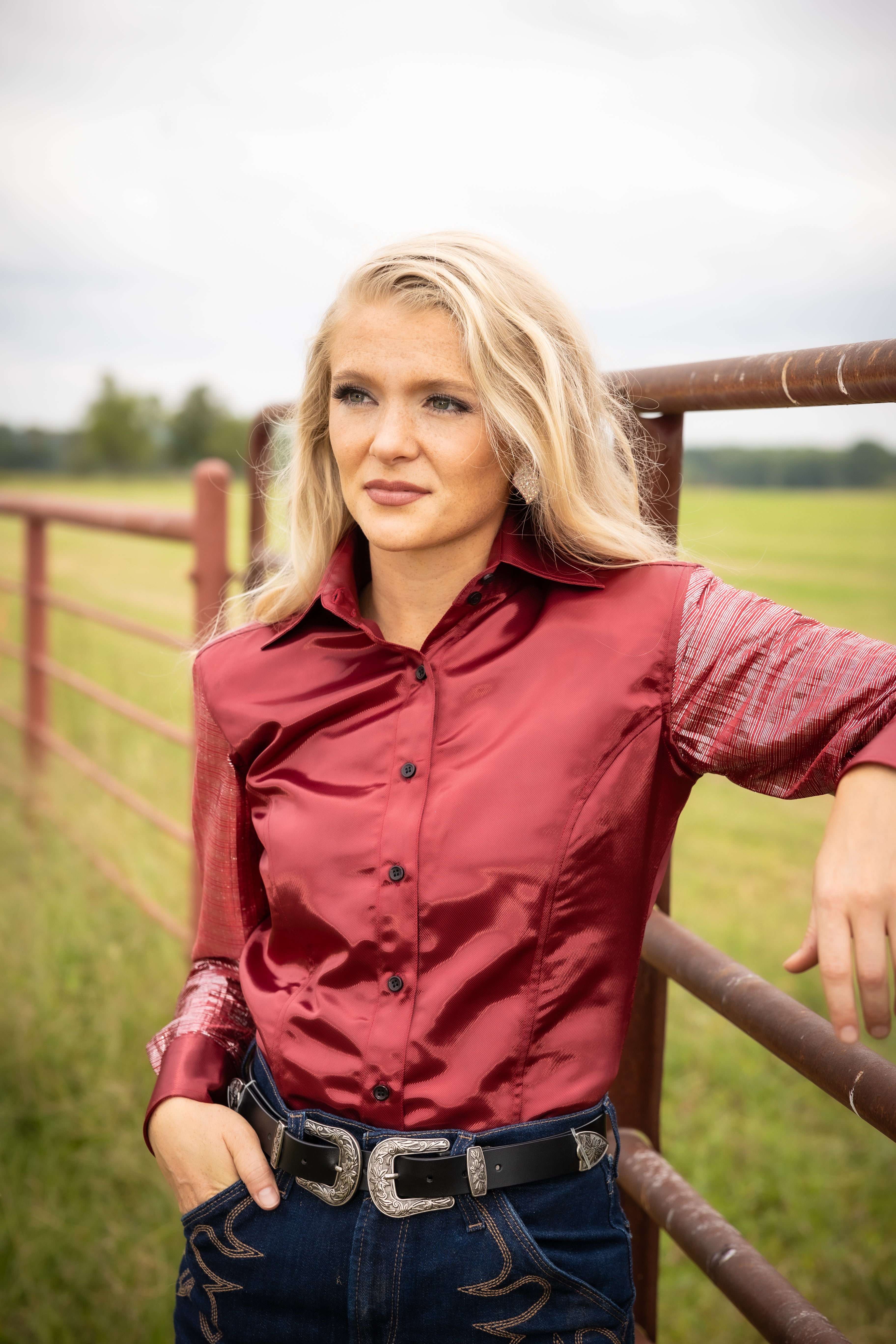 Model posing in Ranch setting wearing Garnet shirt from Kultured Rider's jewel collection.