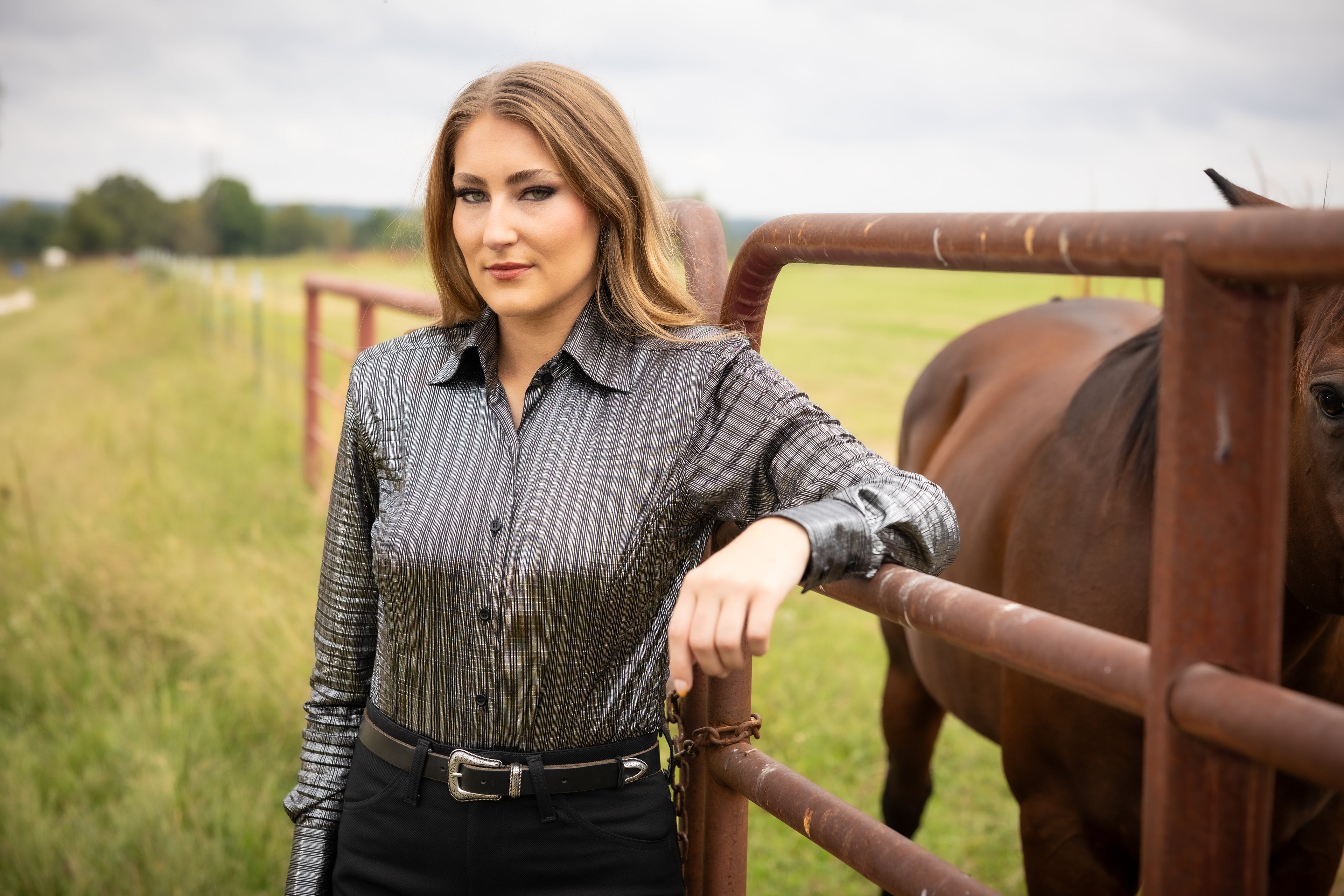 Model posing with horse in ranch setting wearing Onyx shirt from Kultured Rider's jewel collection.