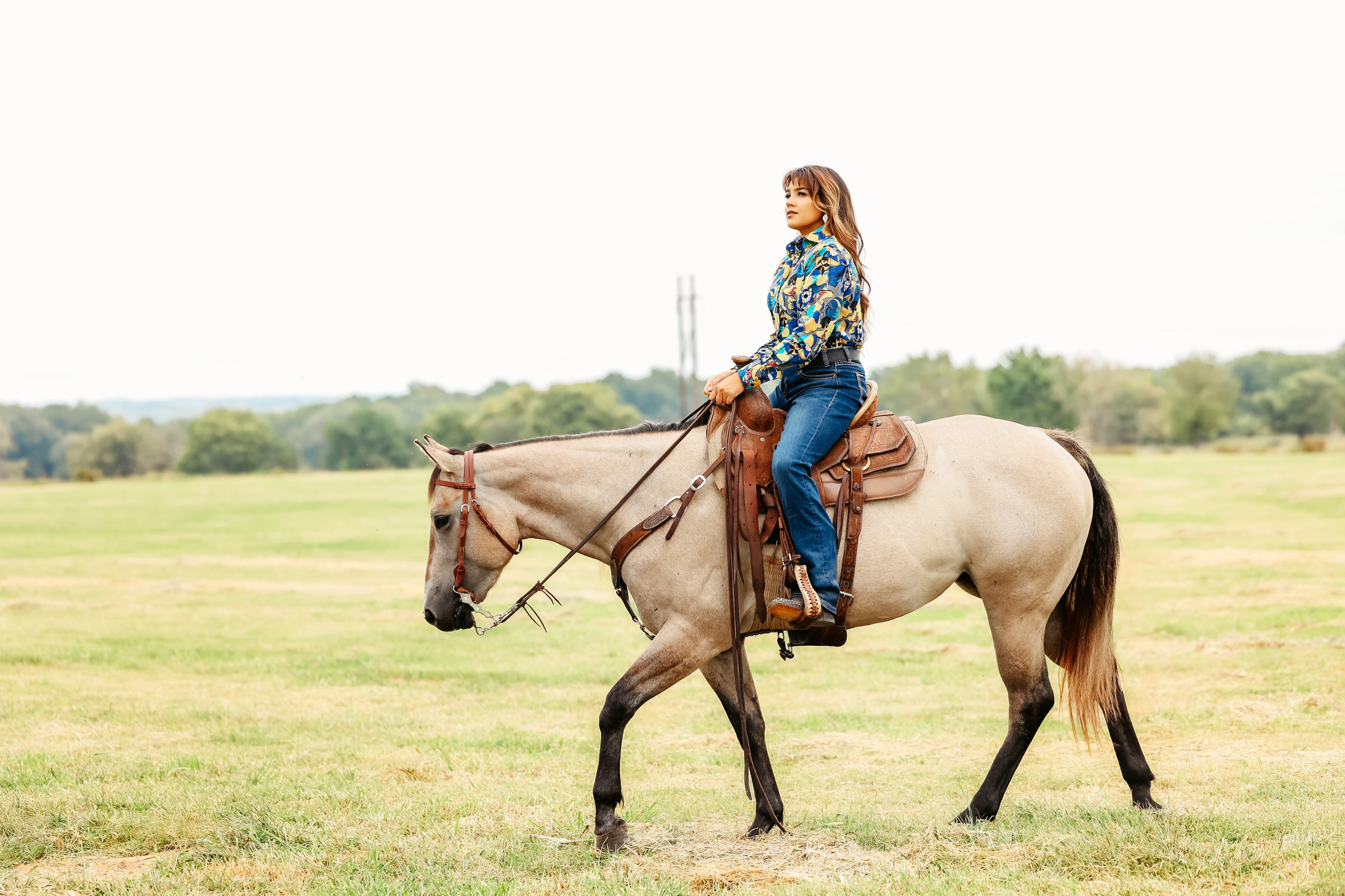 Woman riding a horse in jungle blue shirt from the Romina collection by Kultured Rider.