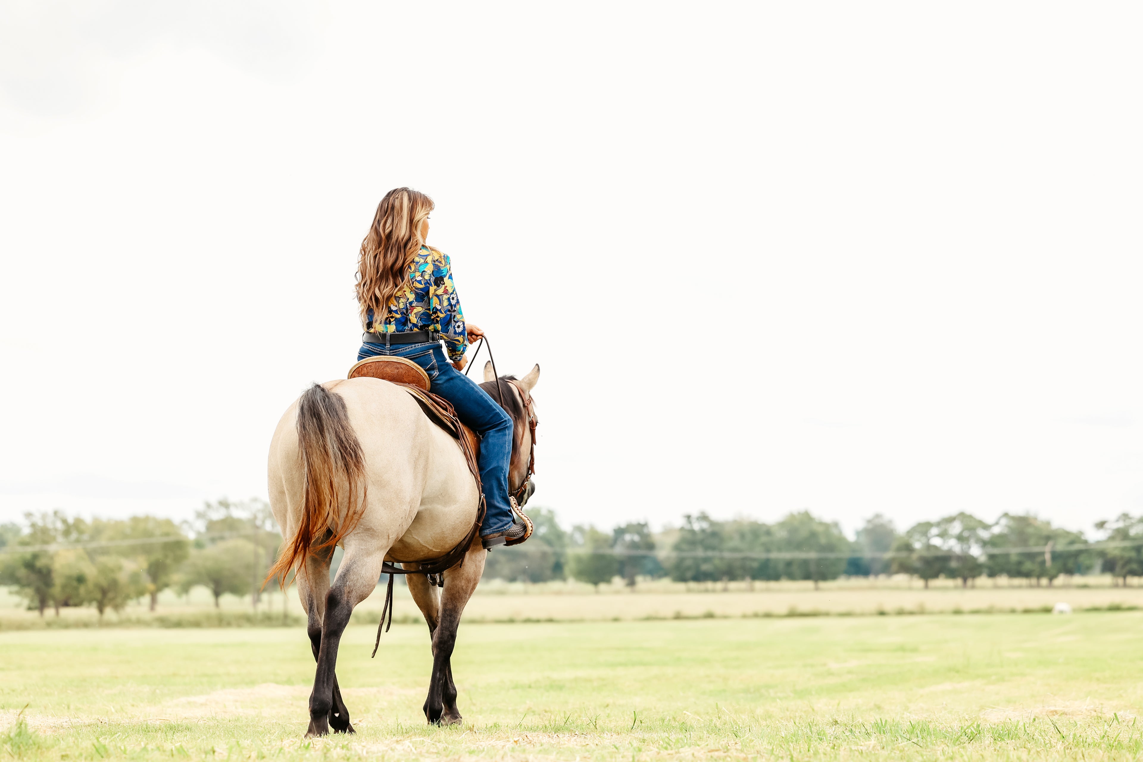 Woman riding a horse in jungle blue shirt from the Romina collection by Kultured Rider.