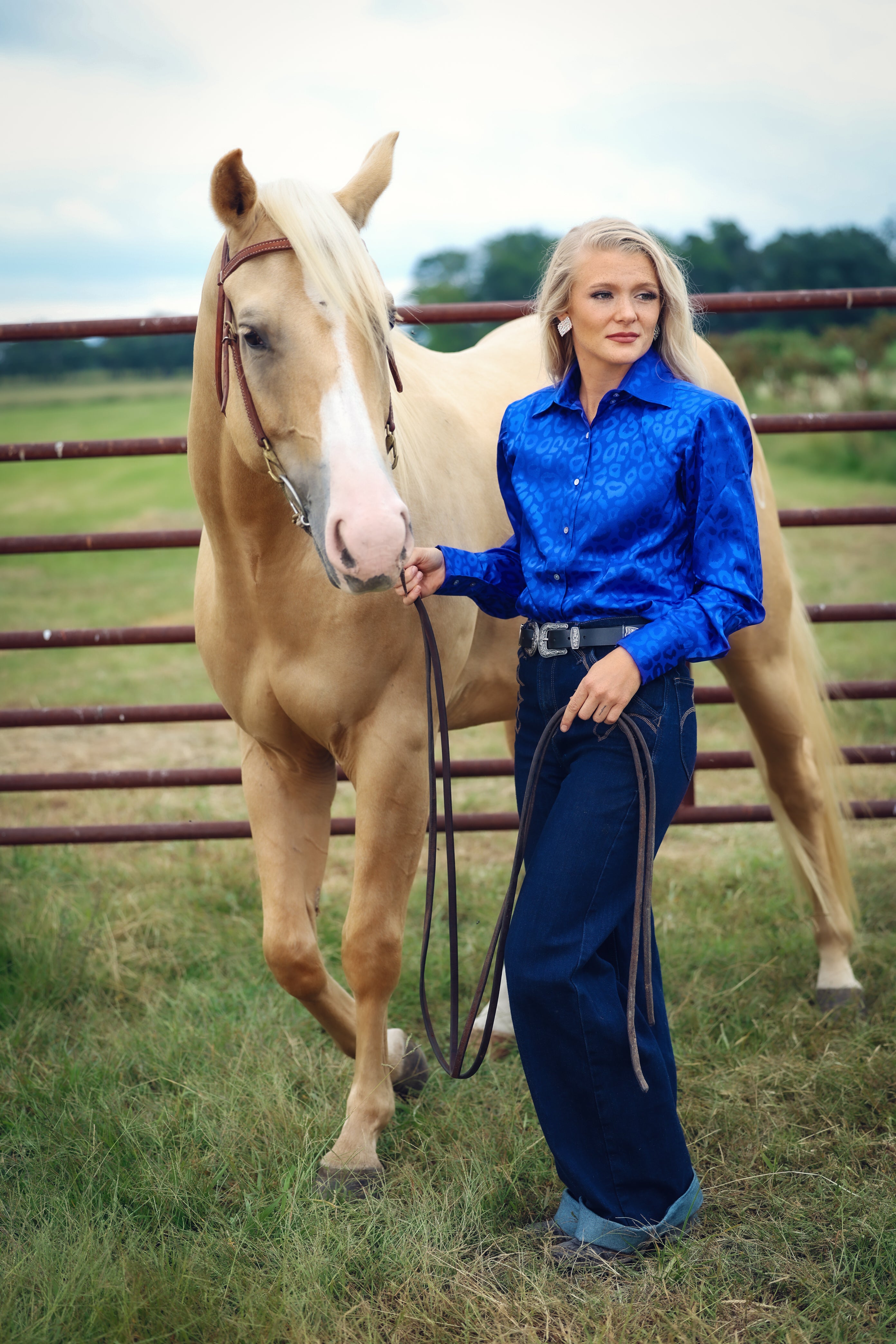 Model with horse posing in leopard blue shirt from the Faith collection by Kultured Rider in a green field.