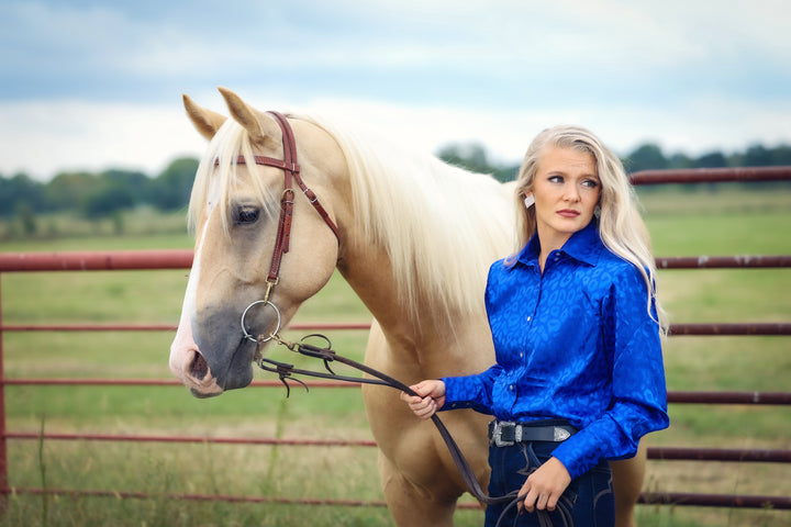 Model with horse posing in leopard blue shirt from the Faith collection by Kultured Rider in a green field.