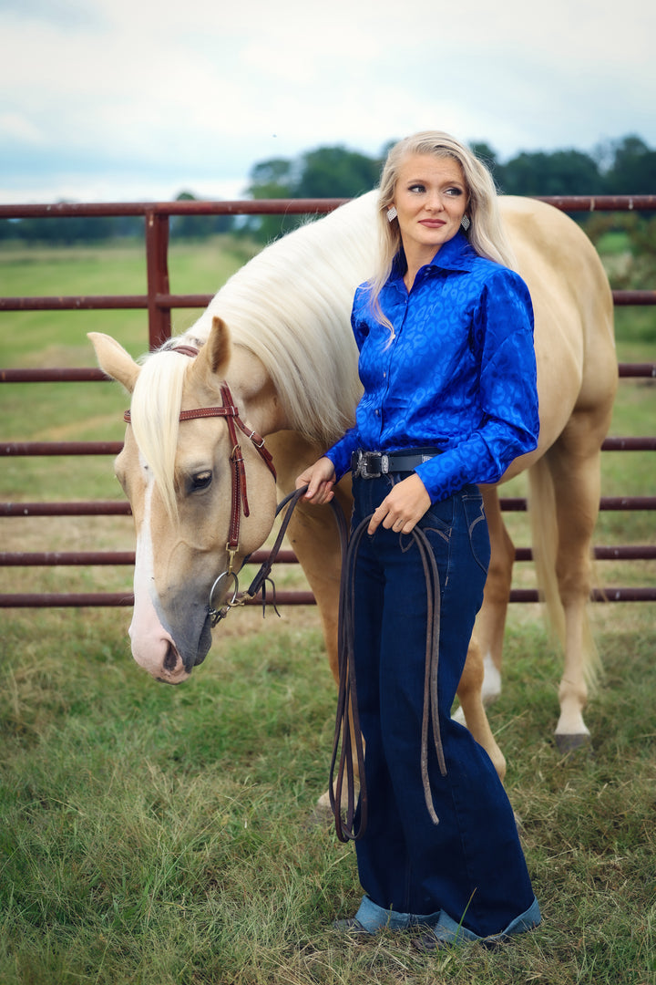 Model with horse posing in leopard blue shirt from the Faith collection by Kultured Rider in a green field.