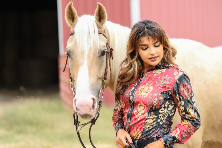 Model displaying red and black velvet riding shirt accompanied by horse.