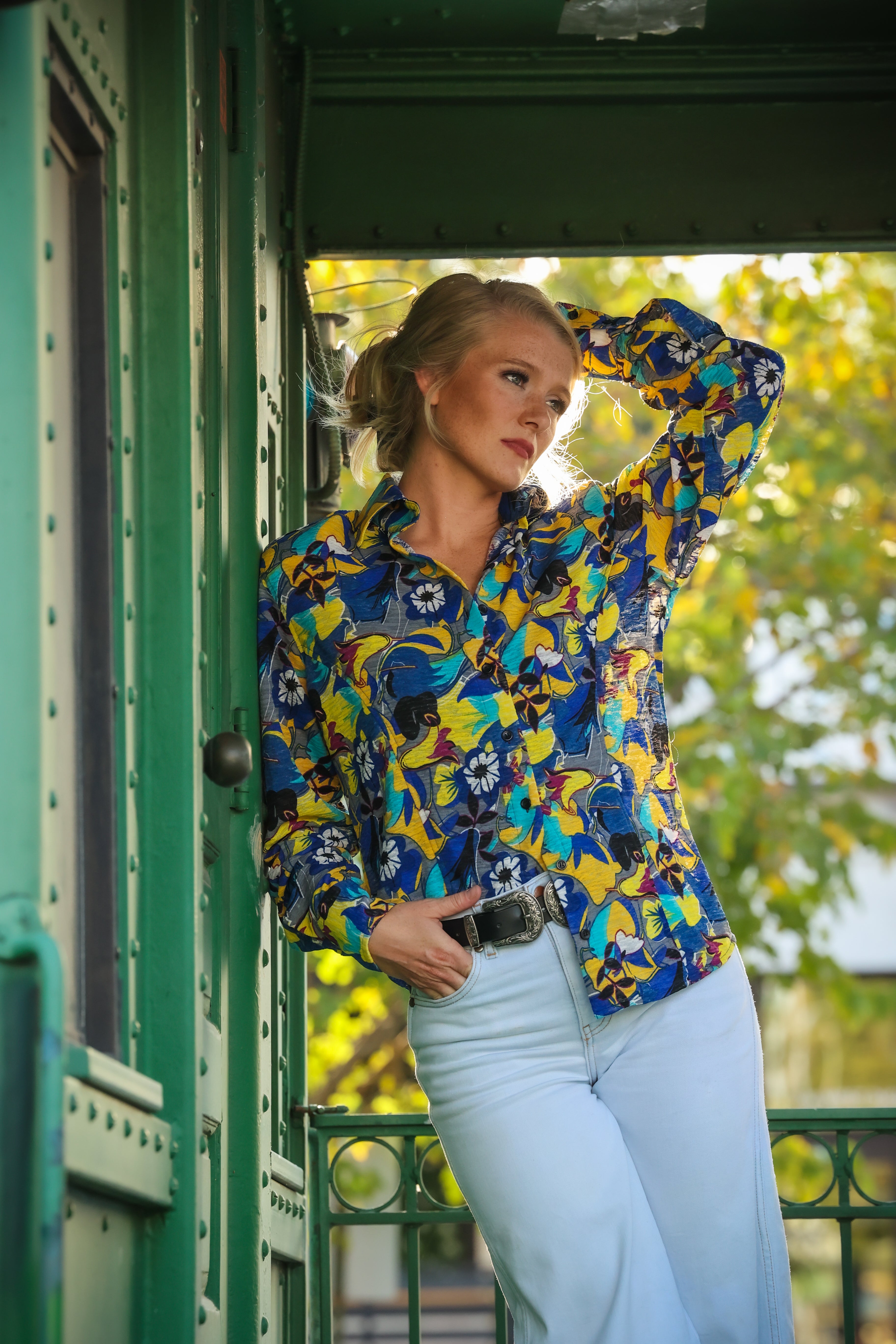 Model posing in jungle blue shirt from the Romina collection by Kultured Rider in front of an urban backdrop.