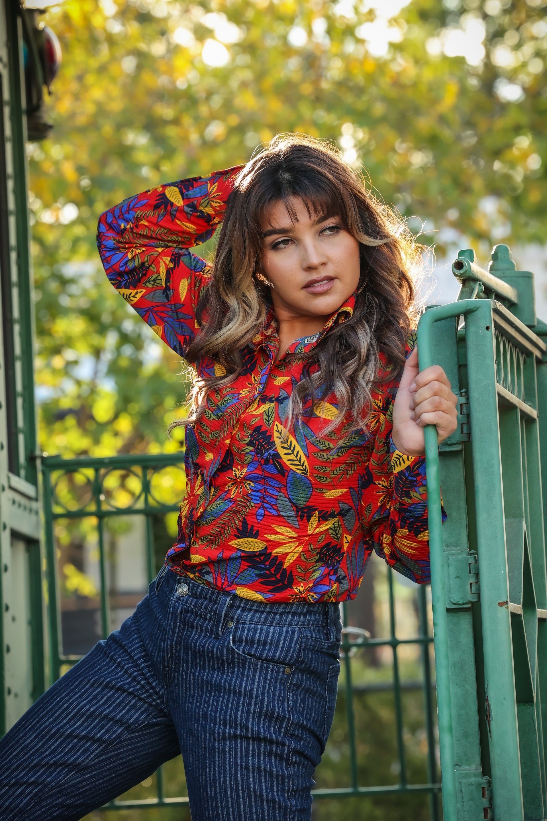 Model posing in jungle red shirt from the Romina collection by Kultured Rider in front of an urban backdrop.