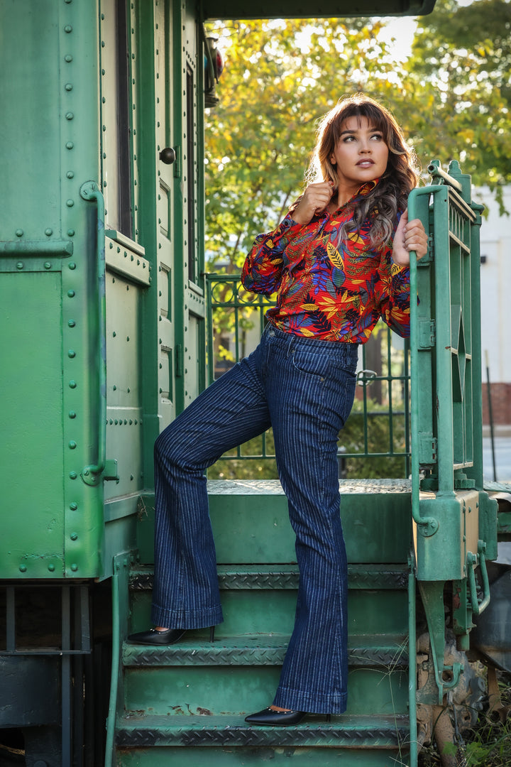 Model posing in jungle red shirt from the Romina collection by Kultured Rider in front of an urban backdrop.